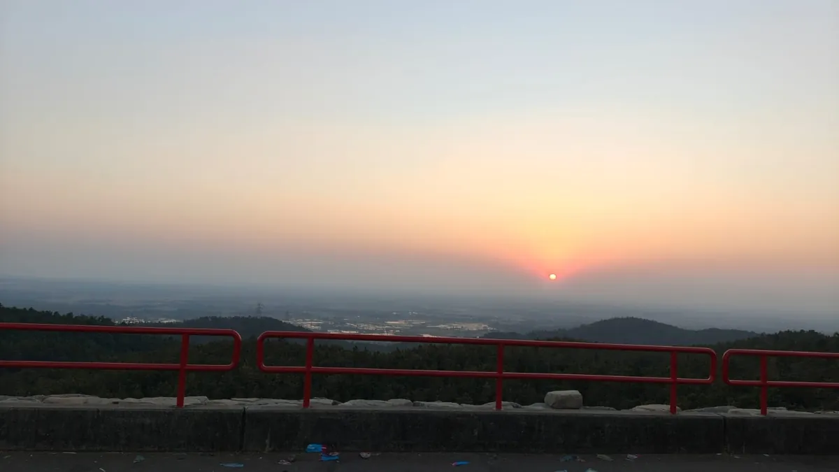 Sunset over distant hills from a railed viewpoint